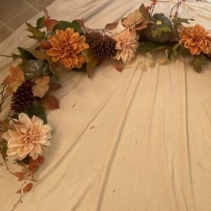 Long, twig bundle, string of autumn leaves, gourds, pumpkins, and pine cones.